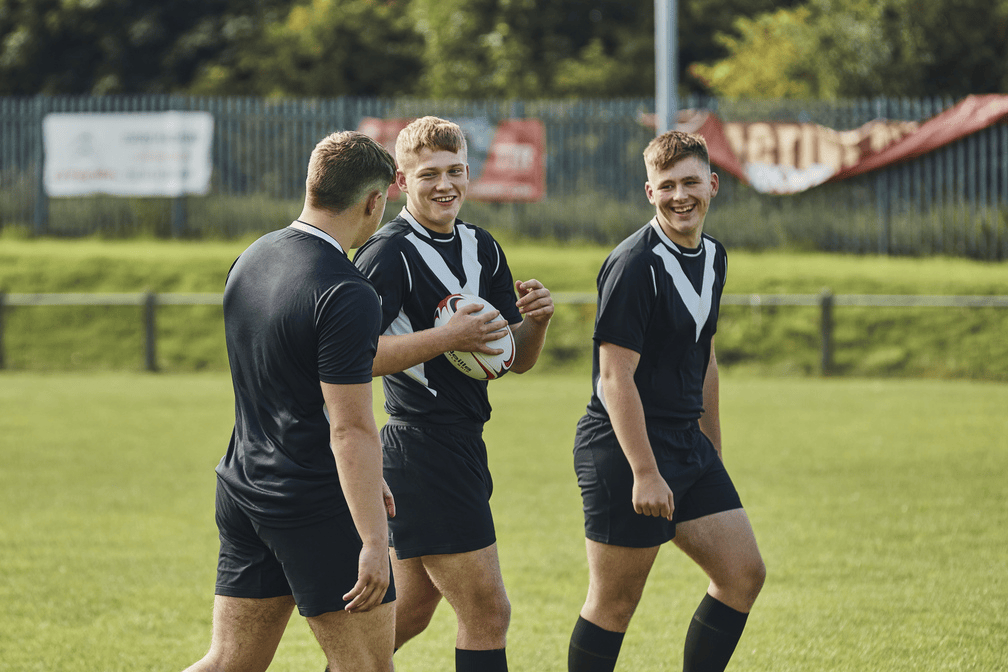 Three men on the rugby field talking